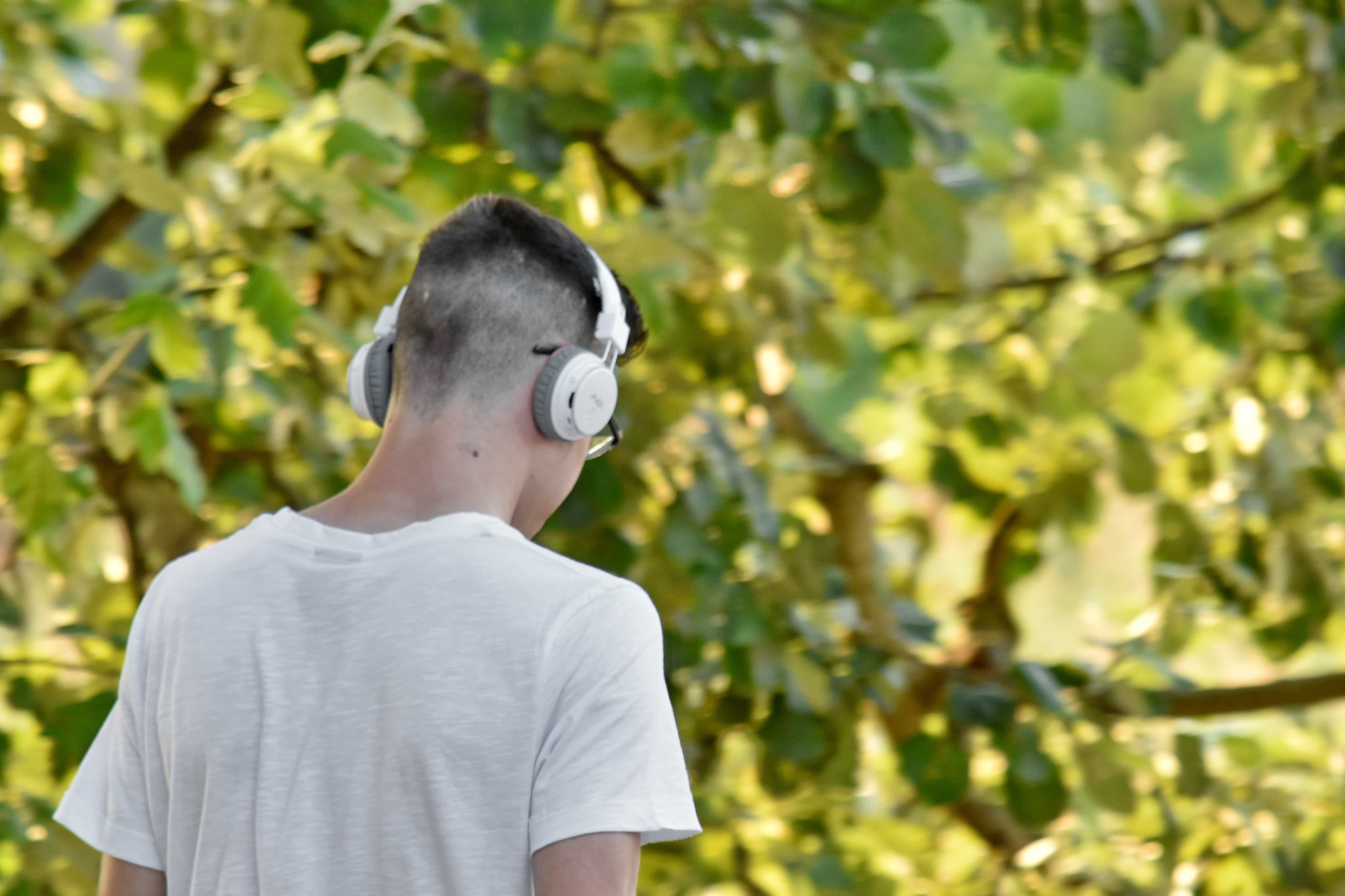 Teenager wearing white over-ear headphones outdoors