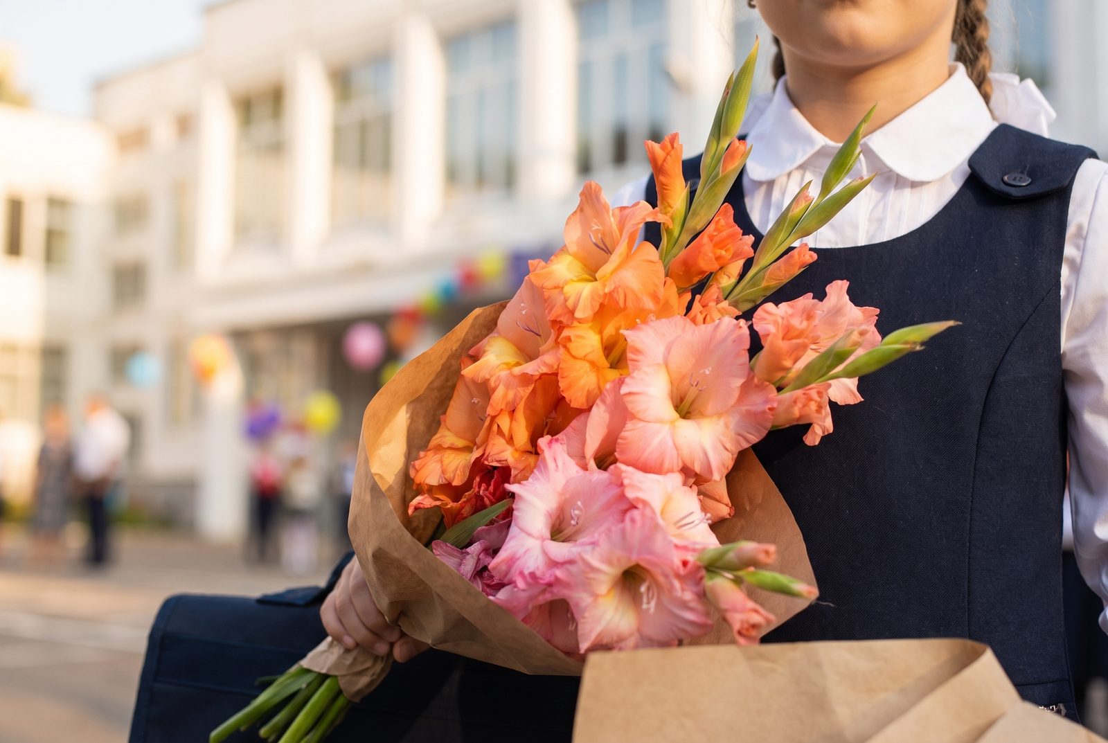 A bouquet of gladioli held by a pupil in school uniform on Knowledge Day